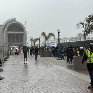 Attendees wait in line on a foggy, overcast, and slightly rainy morning.